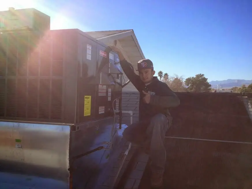 HVAC technician performing Air Duct Repair on a rooftop unit in Wantage