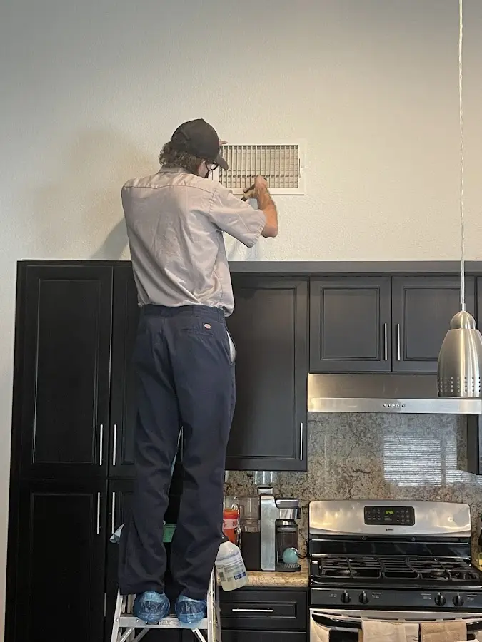 Technician inspecting an air vent during HVAC service in Wantage
